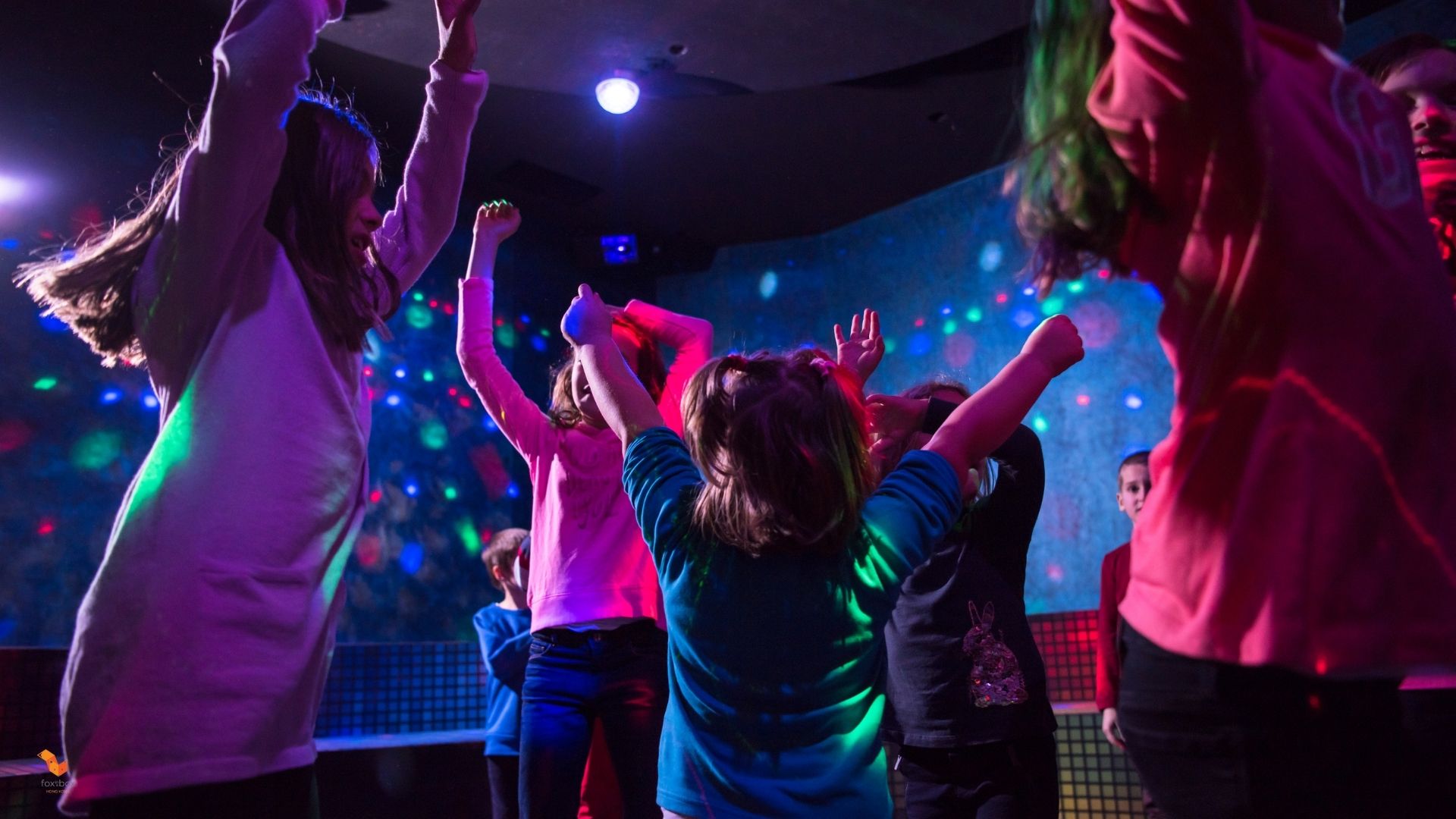 Children playing and interacting in a bright, colorful indoor playground setting.